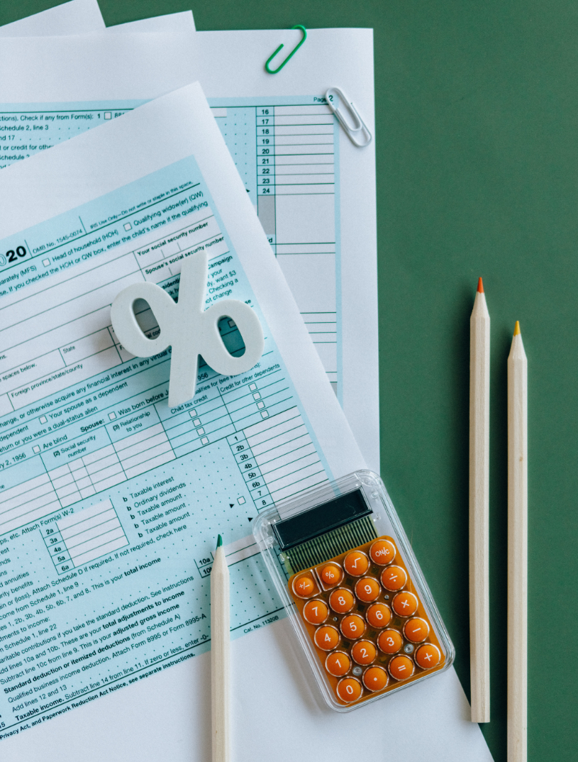 Image of a calculator and pencils beside sample tax forms